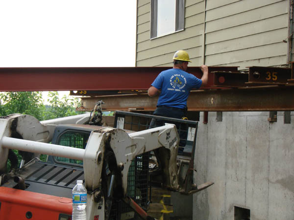 Threading a 12 inch beam under the house and over the temporary beams.